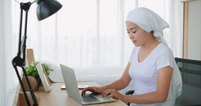 Asian women disease mammary cancer patient wearing headscarf After treatment to chemotherapy with working business at laptop in office at home, medicine concept