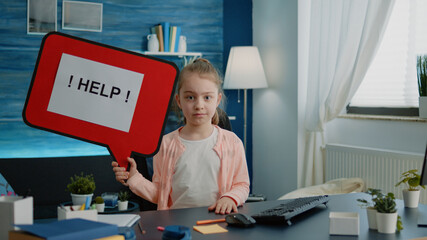 Little child holding speech bubble for help with homework. Schoolgirl sitting at desk with cartoon...