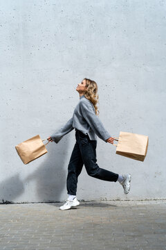 Happy woman walking along street with two shopping bags
