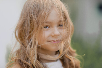 portrait of a cute girl dressed in autumn clothes with hair tangled from the wind