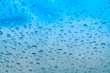 Raindrops on the window. Water droplets on glass. Blue tone