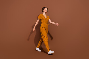Fototapeta na wymiar Full body photo of cheerful happy young woman walk travel empty space good mood isolated on brown color background