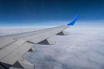 Obraz premium aircraft wing from the aircraft window overlooking the blue sky and beautiful clouds