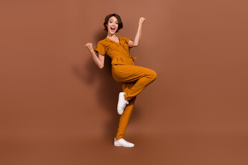 Fototapeta na wymiar Full size photo of cheerful victorious excited good mood raise fists win enjoy isolated on brown color background