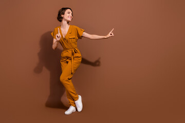 Fototapeta na wymiar Full length photo of cheerful positive dreamy woman look empty space dance enjoy isolated on brown color background