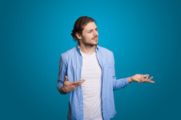 Hipster man on blue wall with long hair posing pensive for fashion lifestyle design. Handsome man. Blue background. Fashionable portrait. Smart look.