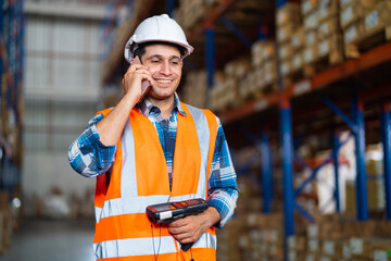 Warehouse worker using a phone holding barcode reader industrial equipment working in a...