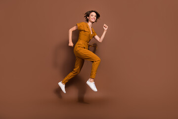 Fototapeta na wymiar Full length photo of cheerful joyful happy young woman jump up run sale season isolated on brown color background