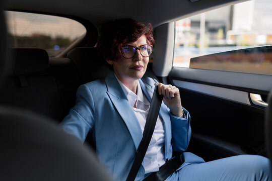 Female professional fastening seat belt while sitting in car