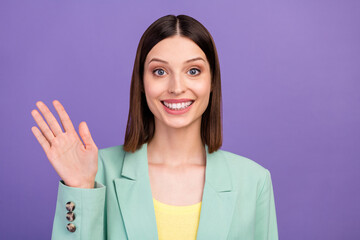 Portrait of satisfied gorgeous person arm palm waving hi look camera beaming smile isolated on violet color background © deagreez