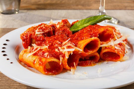 Rigatoni al rag&ugrave; di carne con formaggio grattugiato e basilico fresco serviti come primo piatto in un ristorante
