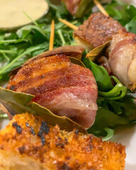 Spiedini di carne con foglie di alloro, crostini di pane e rucola serviti come antipasto