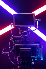 Professional videographer equipment, digital camera with lens in cage. Front view on a black table background.
