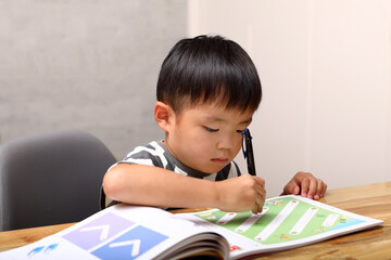 机の上で勉強をする男の子。