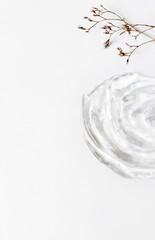 Gel texture of the emulsion on a white background. Transparent cream, small dry flowers and copy space