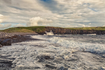 Powerful ocean waves hit rough stone coast. Doolin, county Clare, Ireland. Dark dramatic light and cloudy sky. Irish landscape. Power of nature concept. Dramatic image
