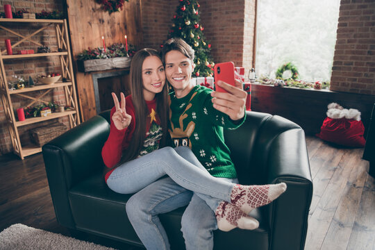 Photo Portrait Young Guy In Ugly Sweater Taking Selfie With Girlfriend Showing V-sign On Couch