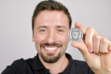 Young caucasian man showing five Swiss francs coin  