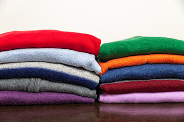Stack of autumn sweaters of different colors, placed on top of each other. Warm clothing and the arrival of autumn and the first cold. 
