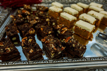 Cookie slices with nuts, cocoa and caramel at buffet table, served on the silver tray