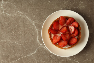 Plate with strawberry tart on gray textured table