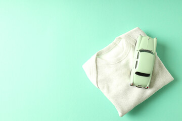 Romper and toy car on mint background