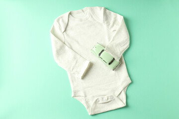 Romper and toy car on mint background
