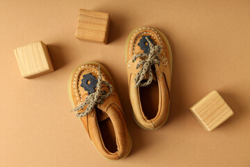 Baby shoes and wooden cubes on beige background