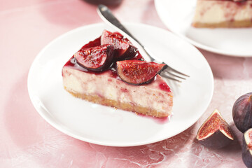 A piece of cake on a white plate on a pink surface: no bake cheesecake with dark red jelly and fig slices