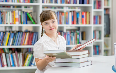 Portrait of a young girl with  Downs syndrome at library.  Education for disabled children concept