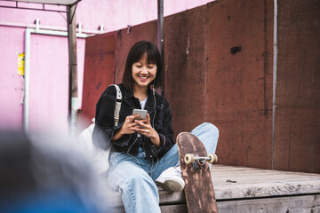 Teenage girl using smart phone while sitting on boardwalk