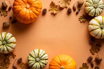 Thanksgiving postcard template. Autumn frame made of pumpkins, dry oak leaves, acorns, cones on orange background. Autumn, fall concept. Flat lay, top view, copy space