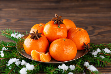 Fototapeta na wymiar Tangerines with anise on a plate with spruce branches.