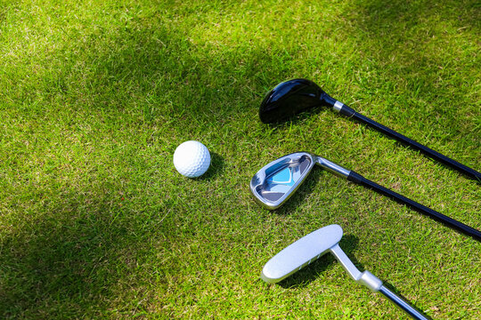 Golf clubs and ball lie on green grass in a rays of the everlasting sun. High quality photo