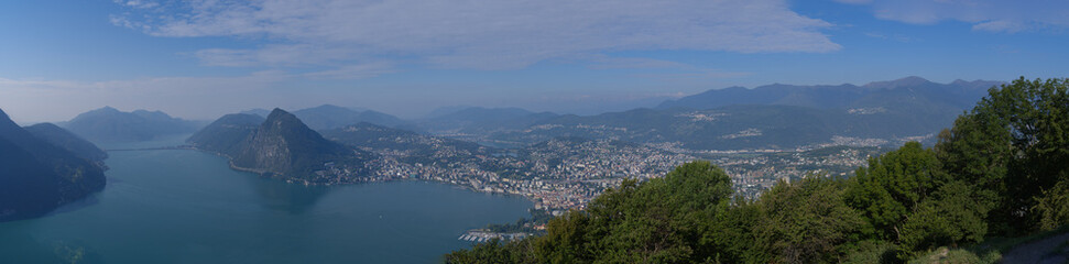 Wide angle aerial view from mountain Monte Brè over Lake Lugano and City of Lugano on a late summer day. Photo taken September 11th, 2021, Lugano, Switzerland.