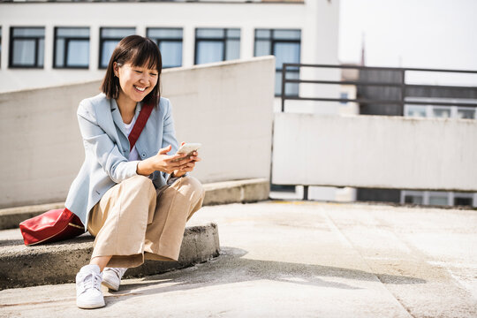 Smiling teenage girl using smart phone during sunny day
