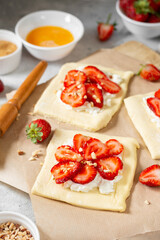 Raw puff pastry with cheese cream and strawberries. The process of making delicious sweet buns