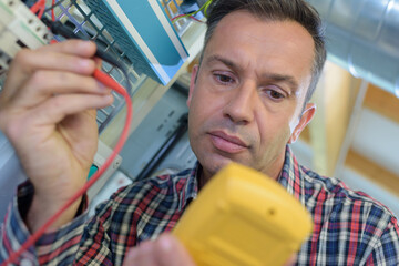 electrician measuring voltage in distribution board