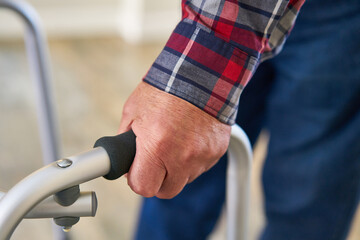 Hand of senior patient grasps the handle of rollator