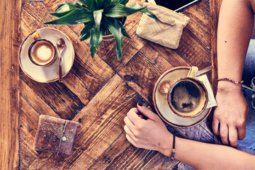 Top view of a coffee shop table with two coffee cups and  woman hands