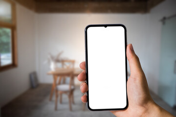 Mockup image of hand holding white mobile phone with blank white screen in cafe.