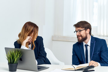 colleagues sitting at the table in front of laptop office technology