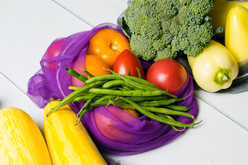 Zero waste, food shopping, eco bags for vegetables and fruits. Vegetables, broccoli, asparagus beans, courgettes, peppers and tomatoes in eco-friendly flat lay bags.