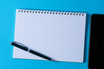 Top view of blank open notebook on blue background and different objects. Minimal flat lay style.