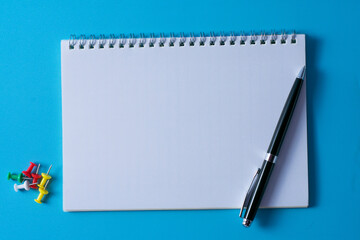 Top view of blank open notebook on blue background and different objects. Minimal flat lay style.