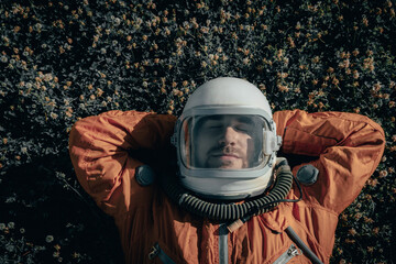 Closeup of cosmonaut wearing space suit and space helmet taking a nap while lying on grass...
