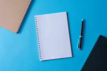 Top view of blank open notebook on blue background and different objects. Minimal flat lay style.