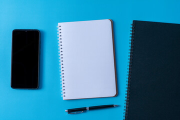 Top view of blank open notebook on blue background and different objects. Minimal flat lay style.