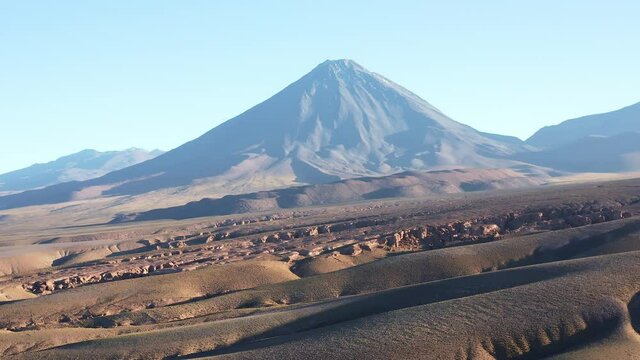 Aerial dolly shot, moving down the mountain, of the volcano Volcan Licancabur east of the town San Pedro de Atacama in the north of Chile in the Atacama desert at sunrise