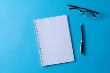 Top view of blank open notebook on blue background and different objects. Minimal flat lay style.